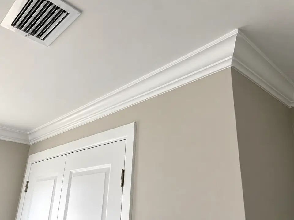 Crown molding meeting a ceiling above a white door