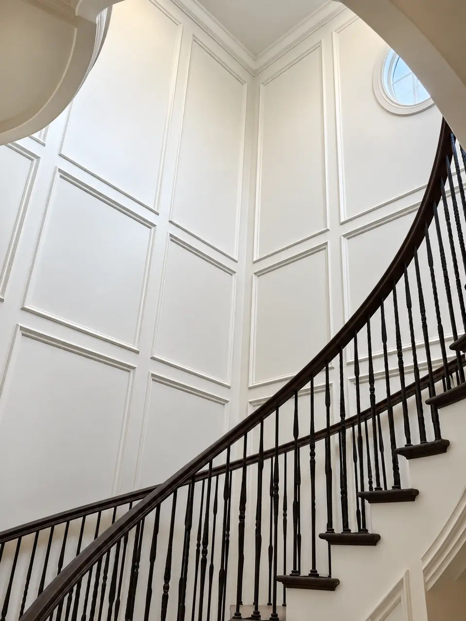 Full-height raised panel molding along a curved staircase