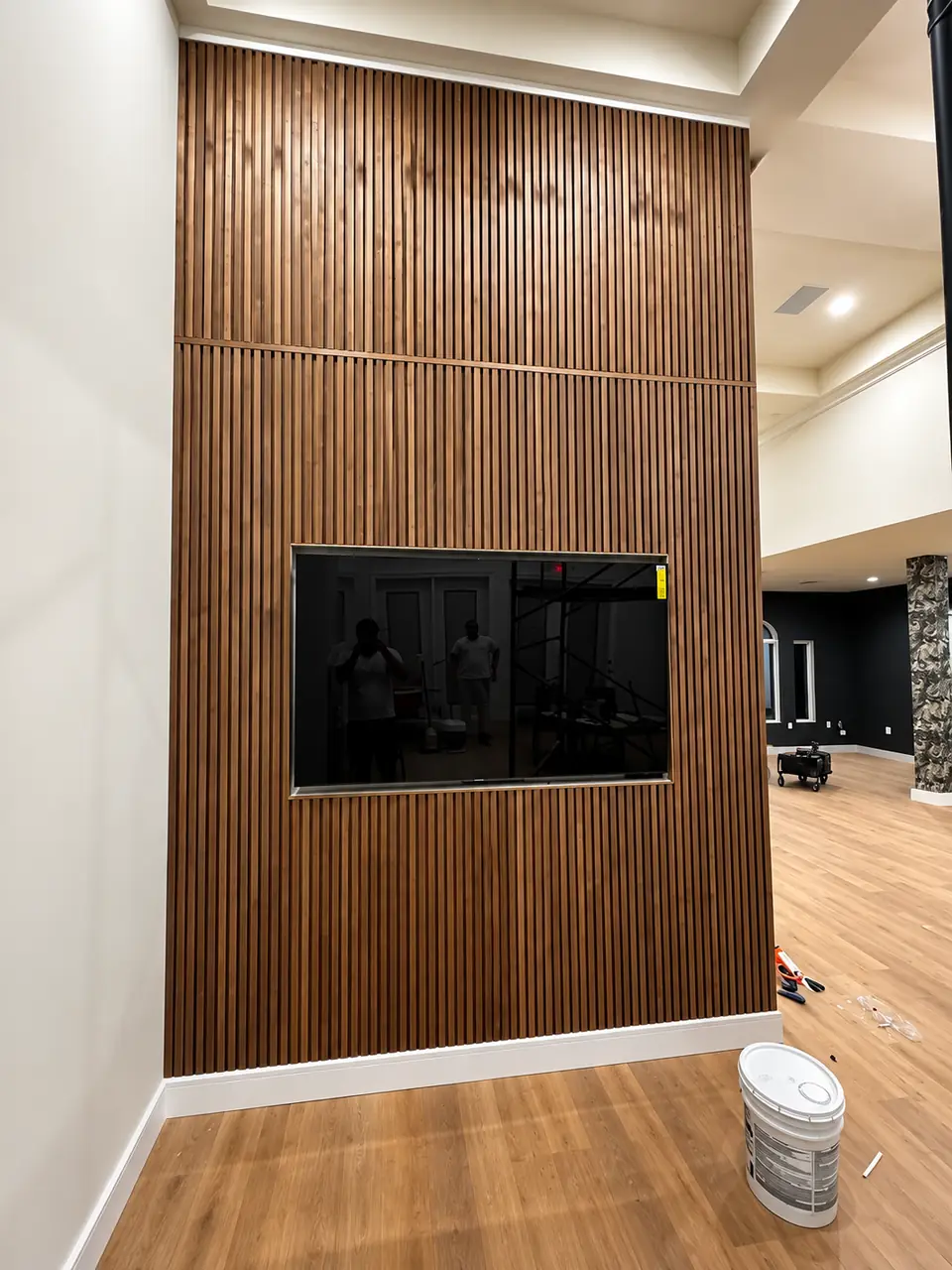 Floor-to-ceiling wood slat feature wall with a mounted TV